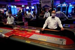 FILE - Dealers in masks wait for customers at the D Las Vegas hotel and casino in Las Vegas, June 3, 2020.