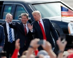 FILE - Then-Georgia Republican gubernatorial candidate Brian Kemp, left, walks with President Donald Trump as Trump arrives for a rally in Macon , Georgia, Nov. 4, 2018.