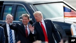 FILE - Then-Georgia Republican gubernatorial candidate Brian Kemp, left, walks with President Donald Trump as Trump arrives for a rally in Macon , Ga. 