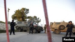 FILE - Israeli security forces stand guard near the scene where a Palestinian, who Israeli military said tried to stab soldiers, was shot dead by Israeli forces at Beit El checkpoint near the West Bank city of Ramallah on February 26, 2016.