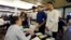 FILE - In this Aug. 14, 2013, file photo, Emilio Ferrer, Brian Ferrer, center, and Jonathan, right, of Hollywood, Florida, talk to a representative at a job fair in Miami Lakes.