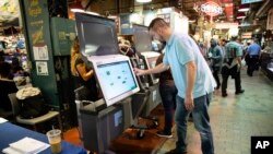 FILE - Steve Marcinkus, an Investigator with the Office of the City Commissioners, demonstrates the ExpressVote XL voting machine at the Reading Terminal Market in Philadelphia, June 13, 2019.