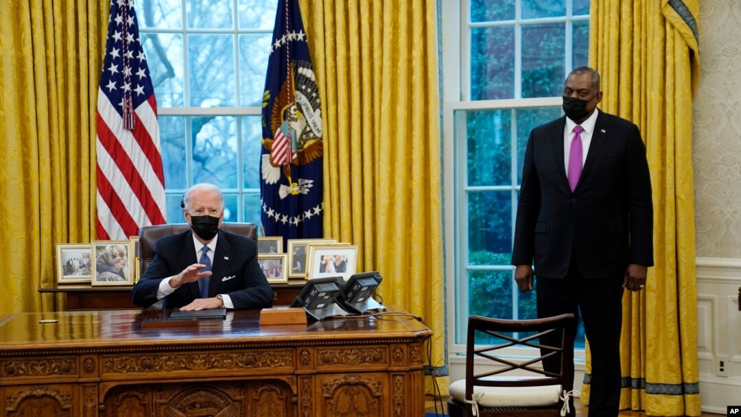 Secretary of Defense Lloyd Austin listens as President Joe Biden speaks before signing an Executive Order reversing the Trump era ban on transgender people serving in the military, in the Oval Office of the White House, Jan. 25, 2021.