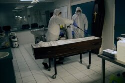 Workers in full protective gear disinfect the casket of a coronavirus victim at the Fontaine funeral home during a partial lockdown to prevent the spread of the disease in Charleroi, Belgium, April 15, 2020.