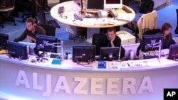 FILE - Al Jazeera English Channel staff prepare for the broadcast in Doha news room in Qatar.