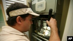 FILE - A home inspector checks air-conditioning coils at a home in the Kendall suburb of Miami. 