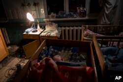 Orphaned children sleep inside cribs at the children's regional hospital maternity ward in Kherson, southern Ukraine on November 22, 2022. (AP Photo/Bernat Armangue)