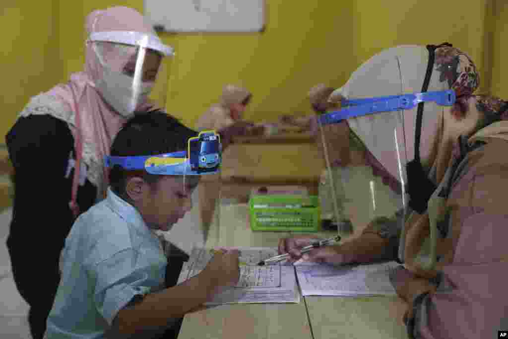 Teachers and students wear protective gear as a precaution against the new coronavirus outbreak during a class at a Quran educational facility at on the outskirts of Jakarta, Indonesia.