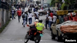 La gente huía de la policía durante los disturbios en reclamo de alimentos en Caracas, Venezuela, el jueves, 2 de junio de 2016.