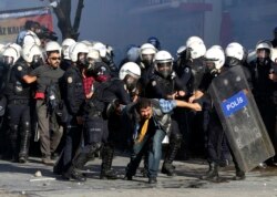 FILE - Turkish riot police detain protesters as they use tear gas to disperse people who were protesting against Turkey's policy in Syria, in Ankara, Turkey, Oct. 7, 2014.