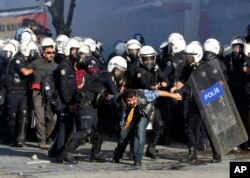 FILE - Turkish riot police detain protesters as they use tear gas to disperse people who were protesting against Turkey's policy in Syria, in Ankara, Turkey, Oct. 7, 2014.