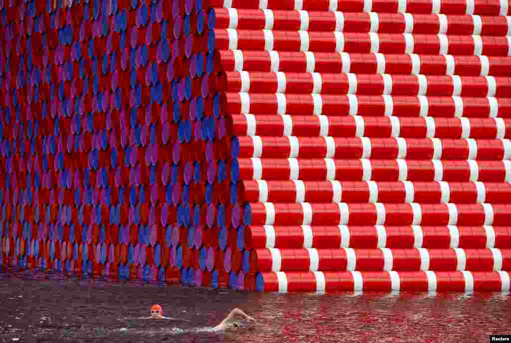 Swimmers exercise in the Serpentine River in front of Christo's "The London Mastaba", in Hyde Park, London.