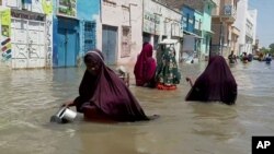 FILE - People wade through a flooded street in Beledweyne, central Somalia, in this image made from video, May 17, 2020. 
