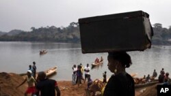 FILE - An unidentified woman carries her belongings on her head after crossing the Mbomou River, which forms part of the boundary between the Central African Republic and the Democratic Republic of the Congo, Feb. 14, 2021.