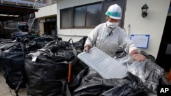 FILE - A worker collects contaminated items for disposal at a private home in Minamisoma, Fukushima prefecture, northeastern Japan, Feb. 24, 2016. 