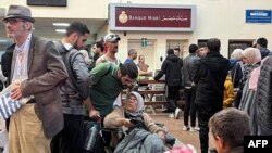 FILE - People fleeing from the Gaza Strip wait in the Egyptian part of the Rafah border crossing on December 3, 2023, amid continuing battles between Israel and the militant group Hamas.