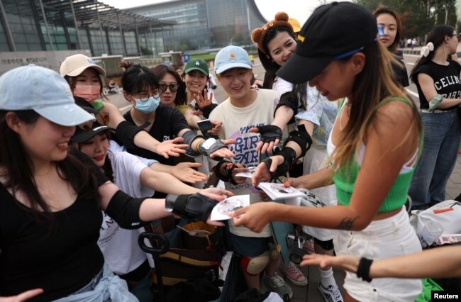 Duo Lan, 31, founder of Beijing Girls Surfskating Community, distributes stickers with the community's logo to the members, during a free weekly training session in Beijing, China, June 18, 2022. (REUTERS/Tingshu Wang)