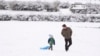 Henry Miller, left, walks in the snow with his father Nate in Nashville, Tennessee, Jan. 11, 2025.