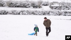 Henry Miller, left, walks in the snow with his father Nate in Nashville, Tennessee, Jan. 11, 2025.