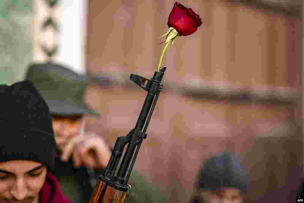 A rose is placed at the tip of the barrel of an assault rifle held by a Syrian rebel fighter before the first weekly Muslim Friday prayers since the ouster of president Bashar al-Assad at the Umayyad mosque in the old city of Damascus.