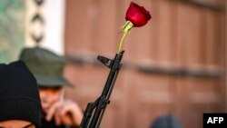 A rose is placed at the tip of the barrel of an assault rifle held by a Syrian rebel fighter before the first weekly Muslim Friday prayers since the ouster of president Bashar al-Assad at the Umayyad mosque in the old city of Damascus.