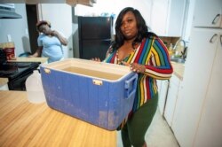 Jennifer Cattenhead shows a cooler with non-potable water she's had to use for flushing water in her home after a recent bout of cold weather caused large numbers of water outages, in Jackson, Mississippi, March 4, 2021.