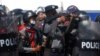 A police officer holds a weapon during clashes with protesters rallying against the military coup and demanding the release of elected leader Aung San Suu Kyi, in Naypyitaw, Myanmar.