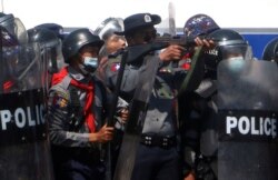 FILE - A police officer holds a weapon during clashes with protesters rallying against the military coup and demanding the release of elected leader Aung San Suu Kyi, in Naypyitaw, Myanmar, Feb. 9, 2021.