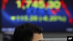 A currency trader reacts as he looks at the monitors at the foreign exchange dealing room of the Korea Exchange Bank headquarters in Seoul, South Korea, August 19, 2011