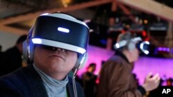 FILE: People look through the first generation prototype of Sony PlayStation VR headsets after a Sony news conference at CES International, Monday, Jan. 8, 2018, in Las Vegas.