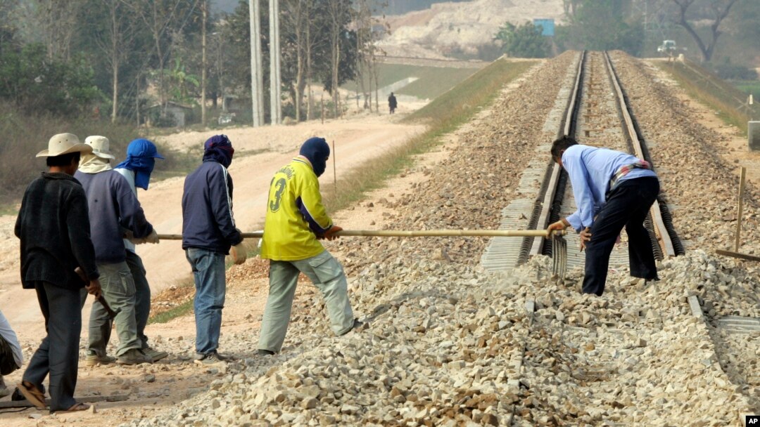 FILE - Construction workers rake gravel on railroad tracks in Thanalaeng, Laos, Feb. 13, 2008.