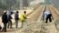 FILE - Construction workers rake gravel on railroad tracks in Thanalaeng, Laos, Feb. 13, 2008.