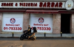 A food delivery scooter passes Barbar Restaurant that now offers food for delivery only, after most of the shops and restaurants closed, Beirut, March 21, 2020.