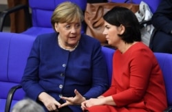German Chancellor Angela Merkel, left, talks to Leader of Germany's Green Party Annalena Baerbock during a meeting of the lower house of parliament in Berlin, Jan. 16, 2020.