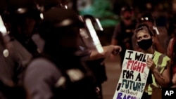 FILE - A protester confronts a line of police in riot gear after a unity march to protest police brutality, in Kansas City, Missouri, June 4, 2020.