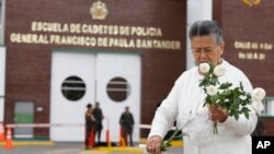 Une femme déposant des fleurs devant l'Académie de police Général Francisco de Paula Santander, au lendemain de l'attentat de l'ELN ayant fait 22 morts à Bogota, Colombie, 18 janvier 2019. (Photo AP/John Wilson Vizcaino)