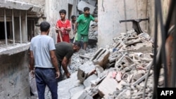 Men search through the rubble of the house of the sister of Ismail Haniyeh, the Doha-based political bureau chief of Hamas, after it was struck in the Shati camp west of Gaza City on June 25, 2024 . The Gaza civil defense agency said 10 members of Haniyeh's family were killed.