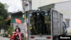 FILE - Vietnamese soldiers look out from a truck as they deliver food in strict lockdown areas amid the COVID-19 pandemic in Ho Chi Minh, Vietnam, August 24, 2021. 