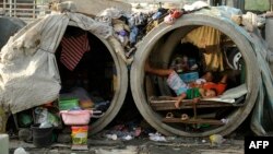 FILE - Families live in concrete pipes used as makeshift dwellings along a street in Manila, March 22, 2016. 