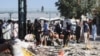 Police officers collect evidence amid the debris after a bomb blast at a railway station in Quetta