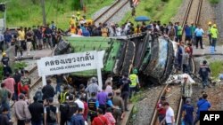 Officials and onlookers gather near the wreckage of an overturned bus involved in a deadly collision with a train next to Khlong Kwaeng Klan railway station in Chachoengsao province, east of the Thai capital Bangkok, Oct. 11, 2020. 