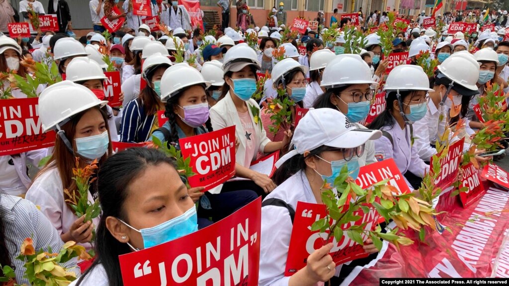 2021年2月21日在曼德勒举行的反政变游行中，医学院学生戴着口罩，举着标语牌聚集在一起。