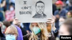 FILE - A demonstrator wearing a protective mask holds up a placard as she attends a protest against racial injustice, following the death of George Floyd at the hands of police in Minneapolis, in Amsterdam, Netherlands, June 10, 2020.