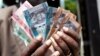 July 19: A man from South Sudan displays new currency notes outside the Central Bank of South Sudan in Juba. South Sudan started rolling out its new currency on Monday: the South Sudan Pound. REUTERS/Benedicte Desrus