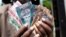 July 19: A man from South Sudan displays new currency notes outside the Central Bank of South Sudan in Juba. South Sudan started rolling out its new currency on Monday: the South Sudan Pound. REUTERS/Benedicte Desrus