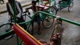 An Indian bicycle rickshaw walla uses a scarf to rest his head while sleeping on his rickshaw in New Delhi. 