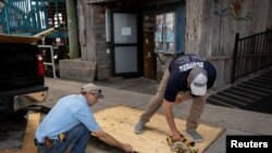 Para pekerja sedang memotong papan untuk persiapan menjelang Badai Idalia, di Cedar Key, Florida, Selasa, 29 Agustus 2023. (Foto: Marco Bello/Reuters)