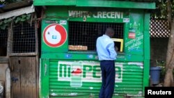 FILE - A customer conducts a transaction at a mobile money transfer stall in Nairobi, Kenya, Oct. 16, 2018. Due to the coronavirus crisis, millions of Africans rely on remittances more so than ever.