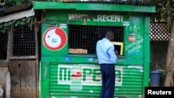 FILE - A customer conducts a transaction at a mobile money transfer stall in Nairobi, Kenya, Oct. 16, 2018. Due to the coronavirus crisis, millions of Africans rely on remittances more so than ever.