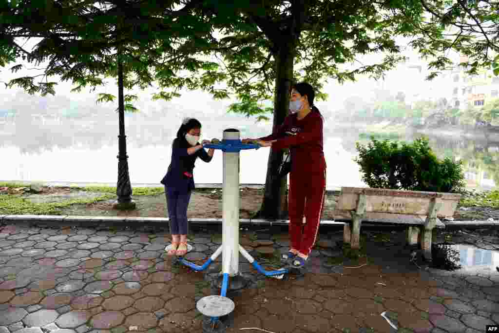 Una niña y su madre usando mascarillas en un área pública al aire libre en Hanoi, en medio del esfuerzo de aislamiento social a nivel nacional de Vietnam como medida preventiva contra la propagación del virus.